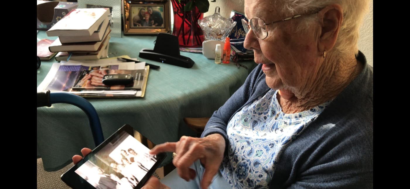 Great-aunt pointing at a photo on a tablet during a reminiscence session